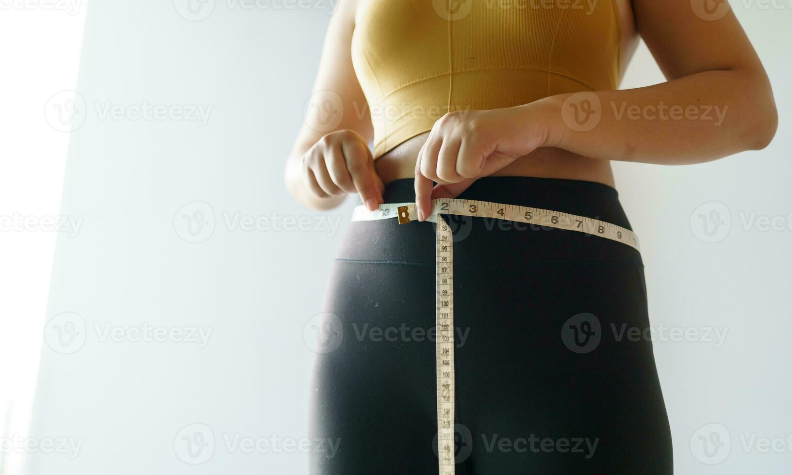 woman want to lose weight with a centimeter Shape up healthy stomach muscle and diet measuring waist with measure tape after diet weight control photo