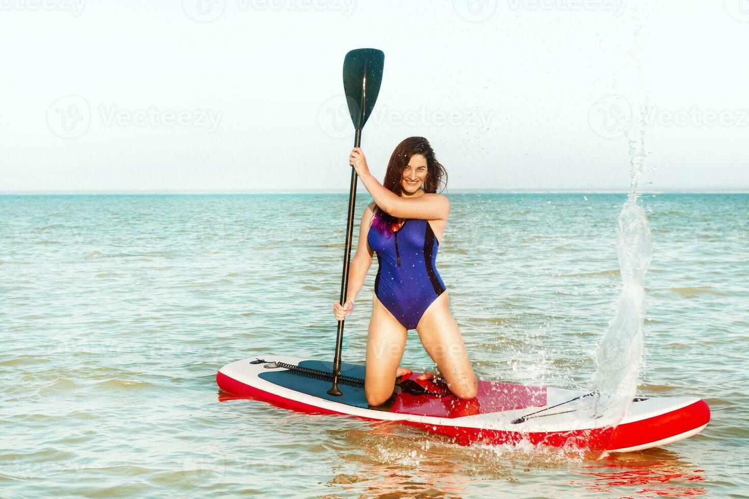 Woman splashes water with an oar on SUP-surfing board in the sea in hot summer. Sup surfing. Summer sport activity Having FUN photo