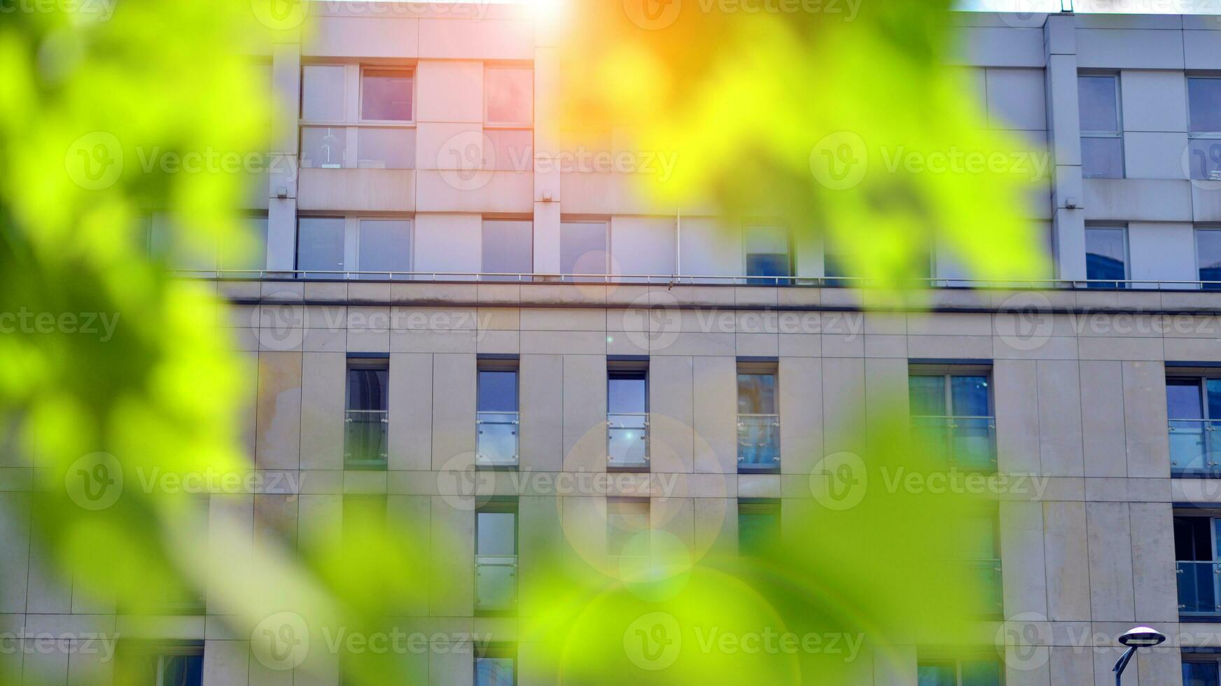 Modern residential building with new apartments in a green residential area. Eco architecture. Green tree and new apartment building. The harmony of nature and modernity. photo