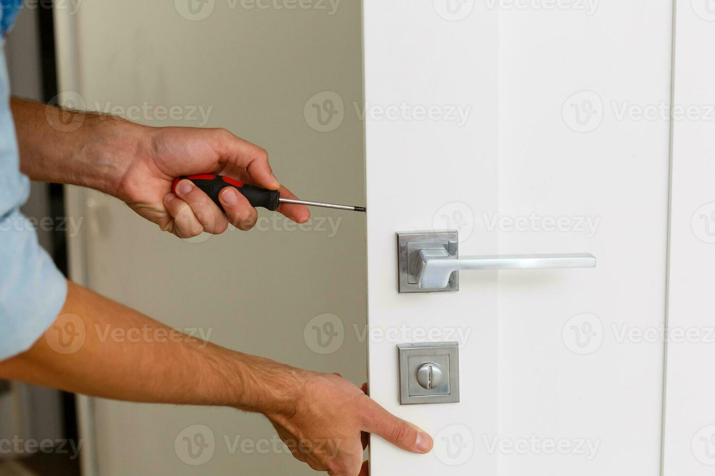 Master with screwdriver installs door hinges. photo