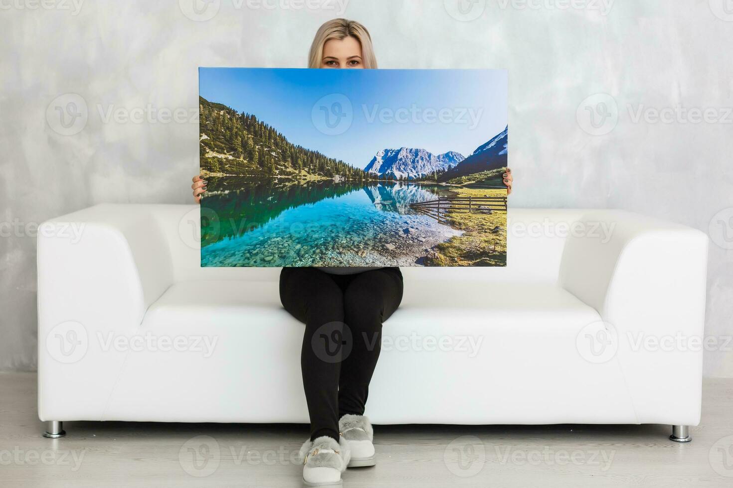 Young girl holds photo canvas at home on the couch