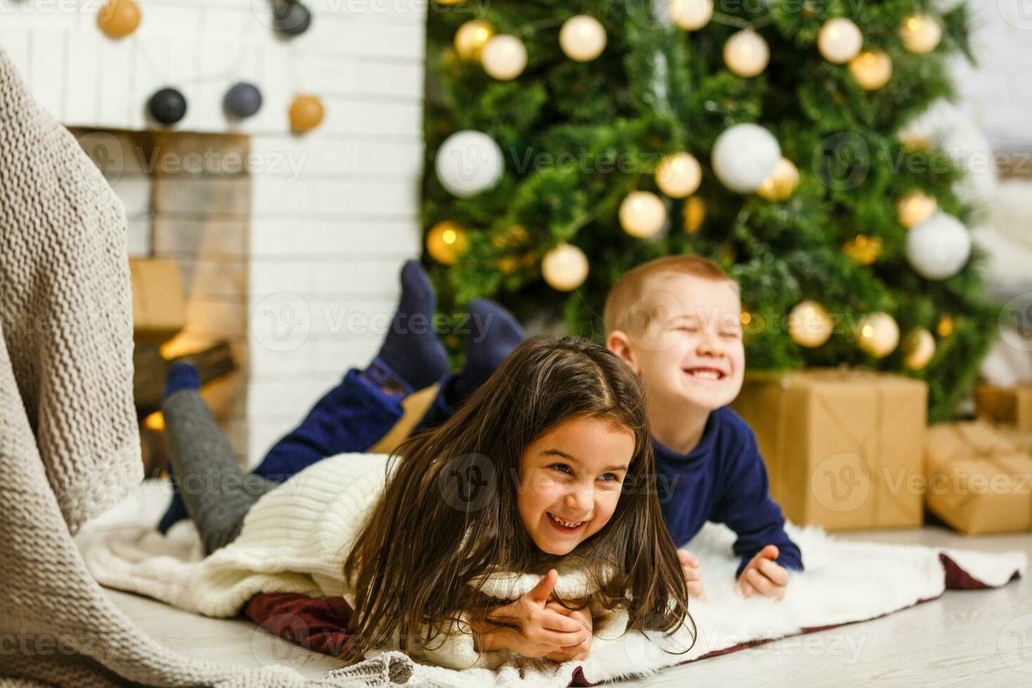 Happy little kids decorate Christmas tree in beautiful living room with traditional fire place. Children opening presents on Xmas eve. photo