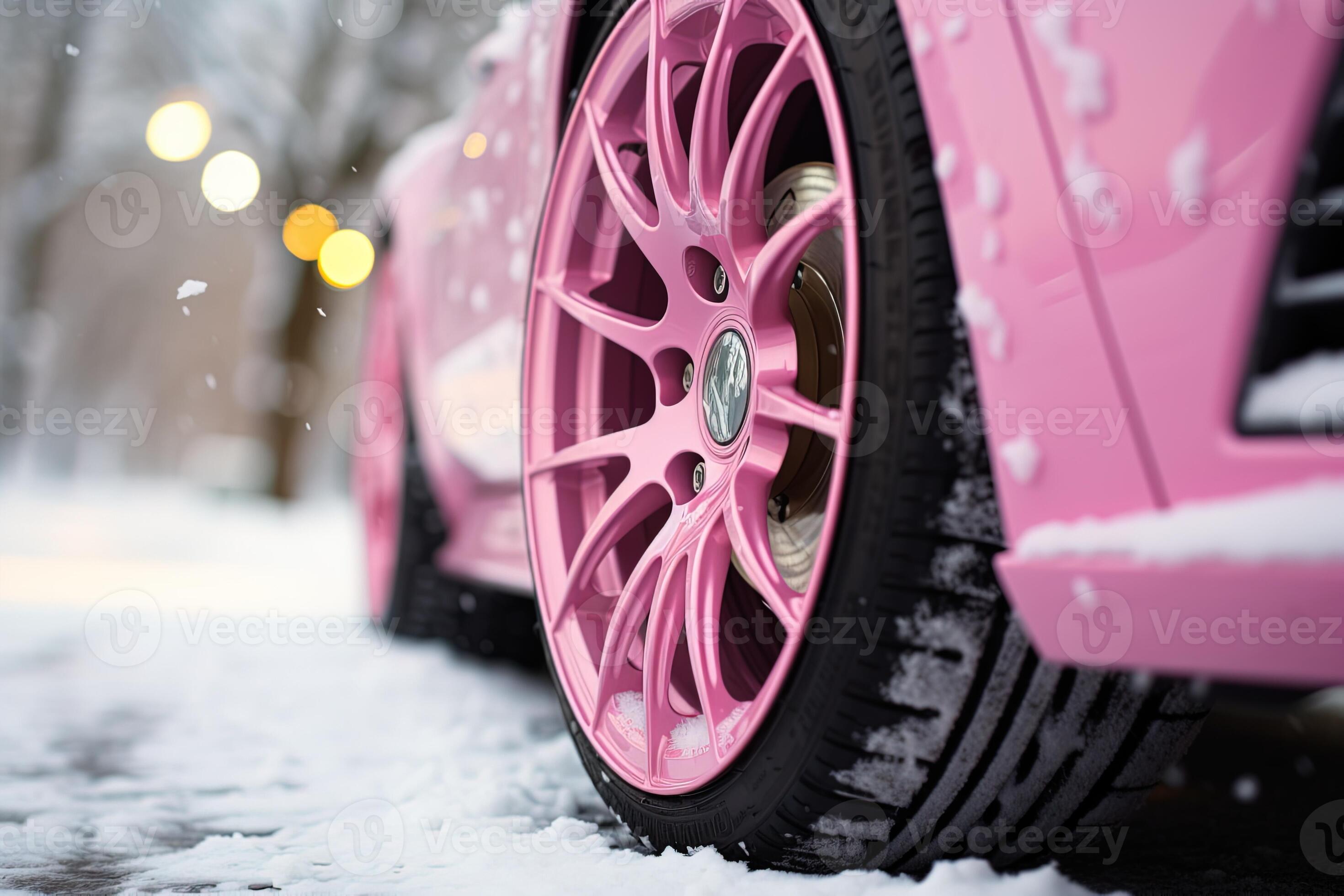 side view of wheels with winter tires on a pink car on a snowy road