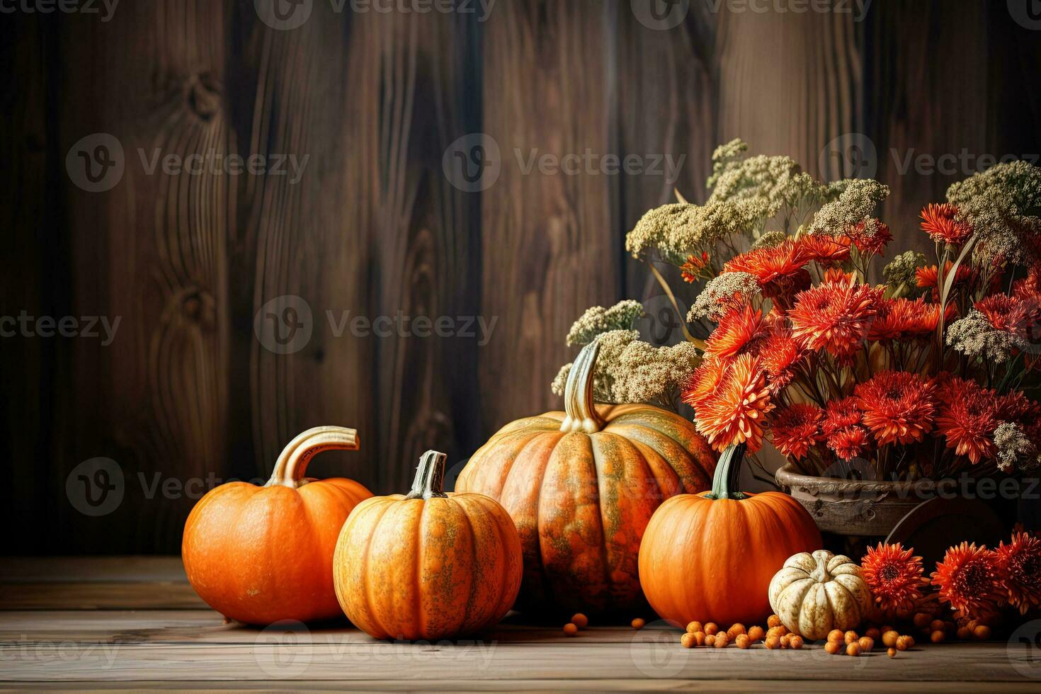 Ripe orange pumpkins lie in a pile near red flowers on a dark wooden surface. Thanksgiving, halloween background photo