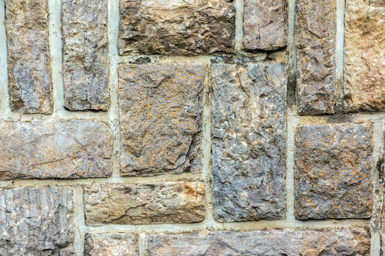 Cobble brown stone siding tile wall abstract background. House exterior with blocks tiled with cement . Crafted brickwork outer wall. photo