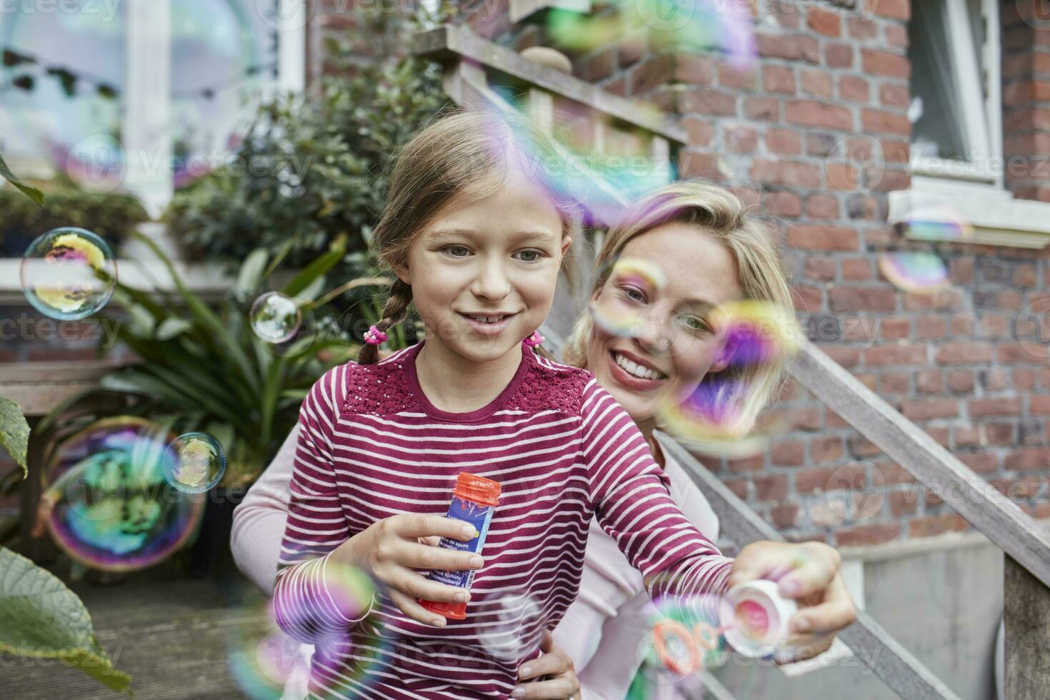 Happy mother and daughter making soap bubbles photo