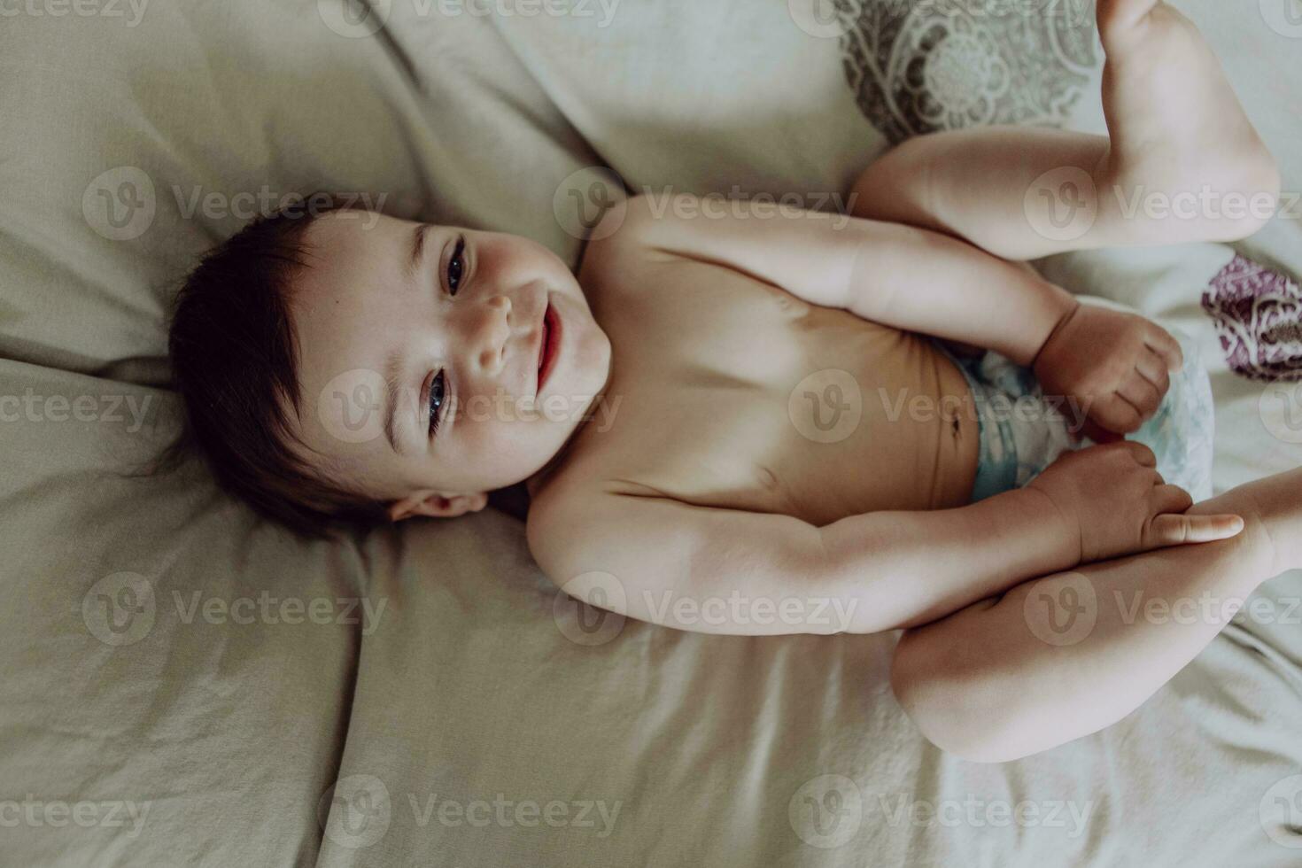 Happy baby, lying on bed, laughing photo