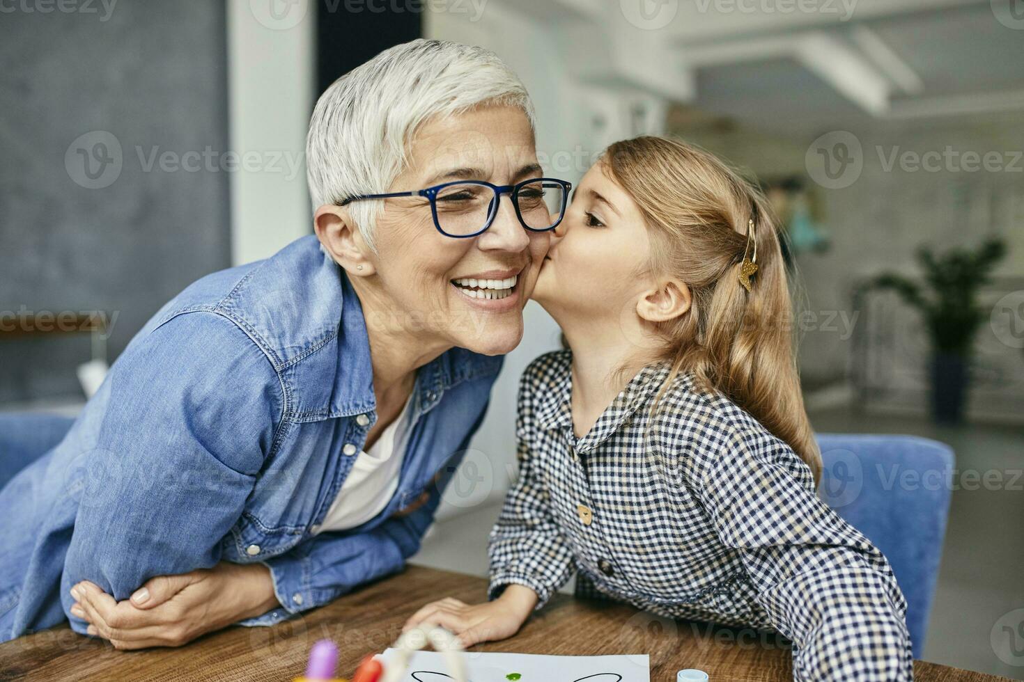 Grandduafghter kissing grandmother, painting colouring book with her photo