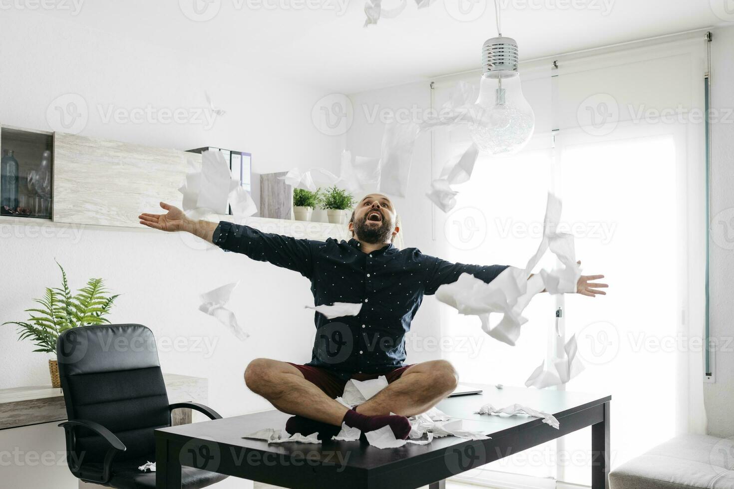 Mischievous boy playing with toilet paper on desk in home office photo