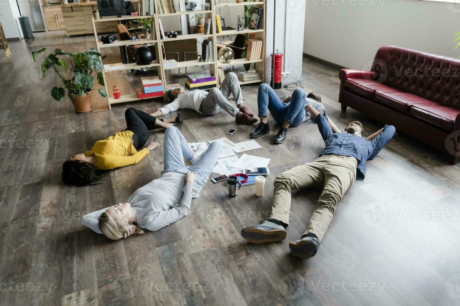 Business team lying on the floor surrounded by documents in loft office photo
