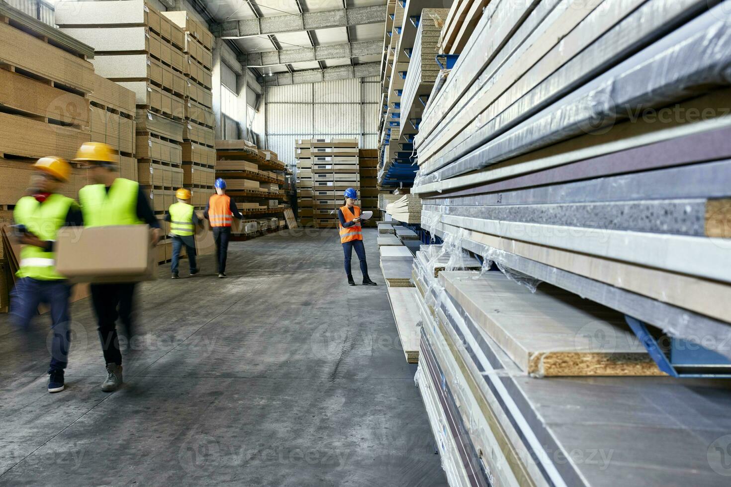 Workers moving and carrying boxes in factory warehouse photo