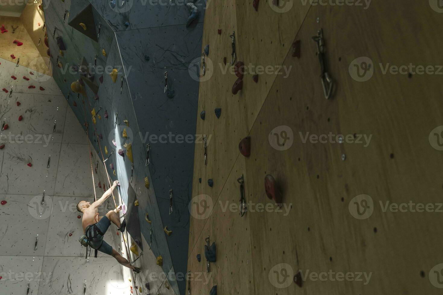 Shirtless man climbing on the wall in climbing gym photo