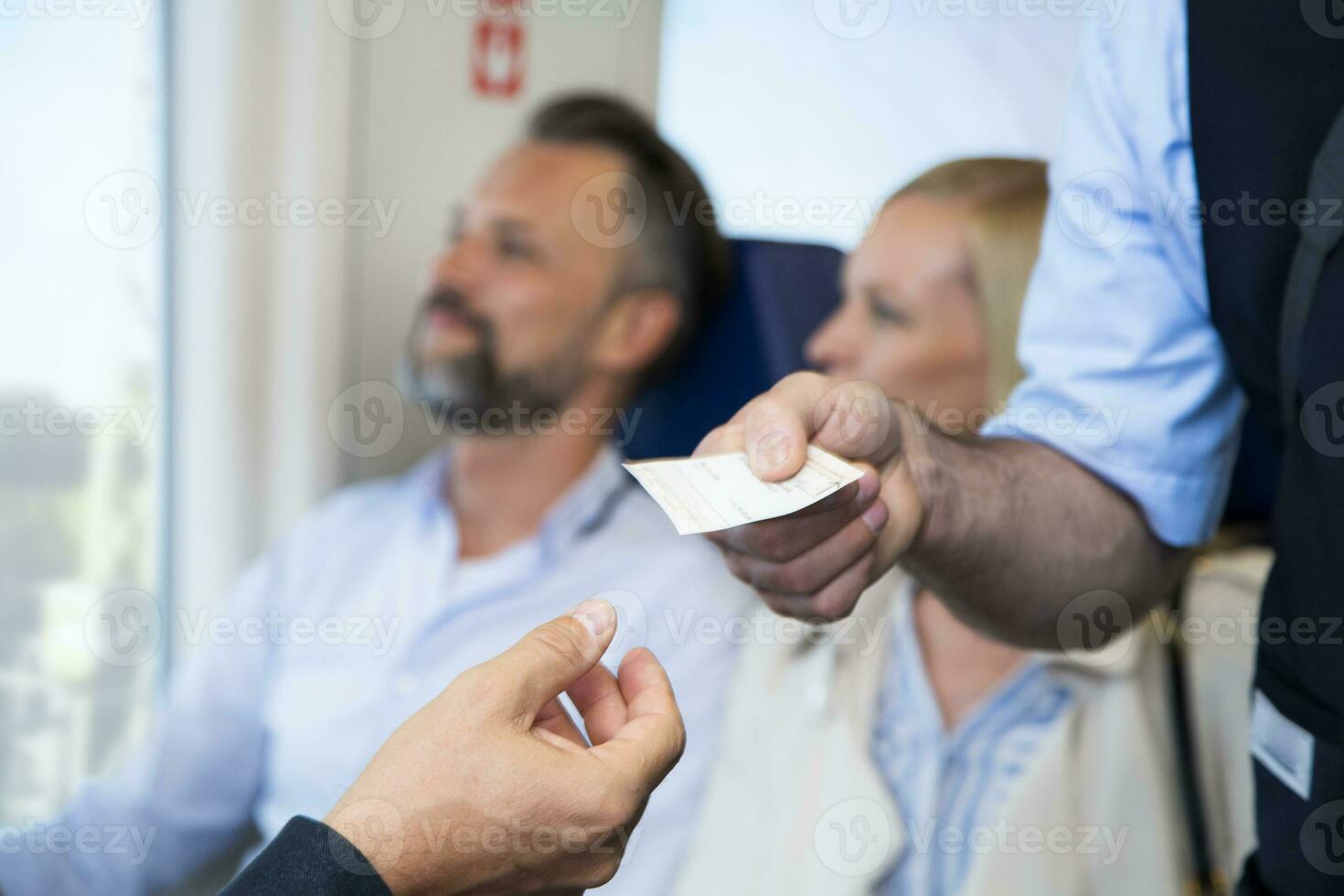 Conductor checking tickets of passengers in a train photo