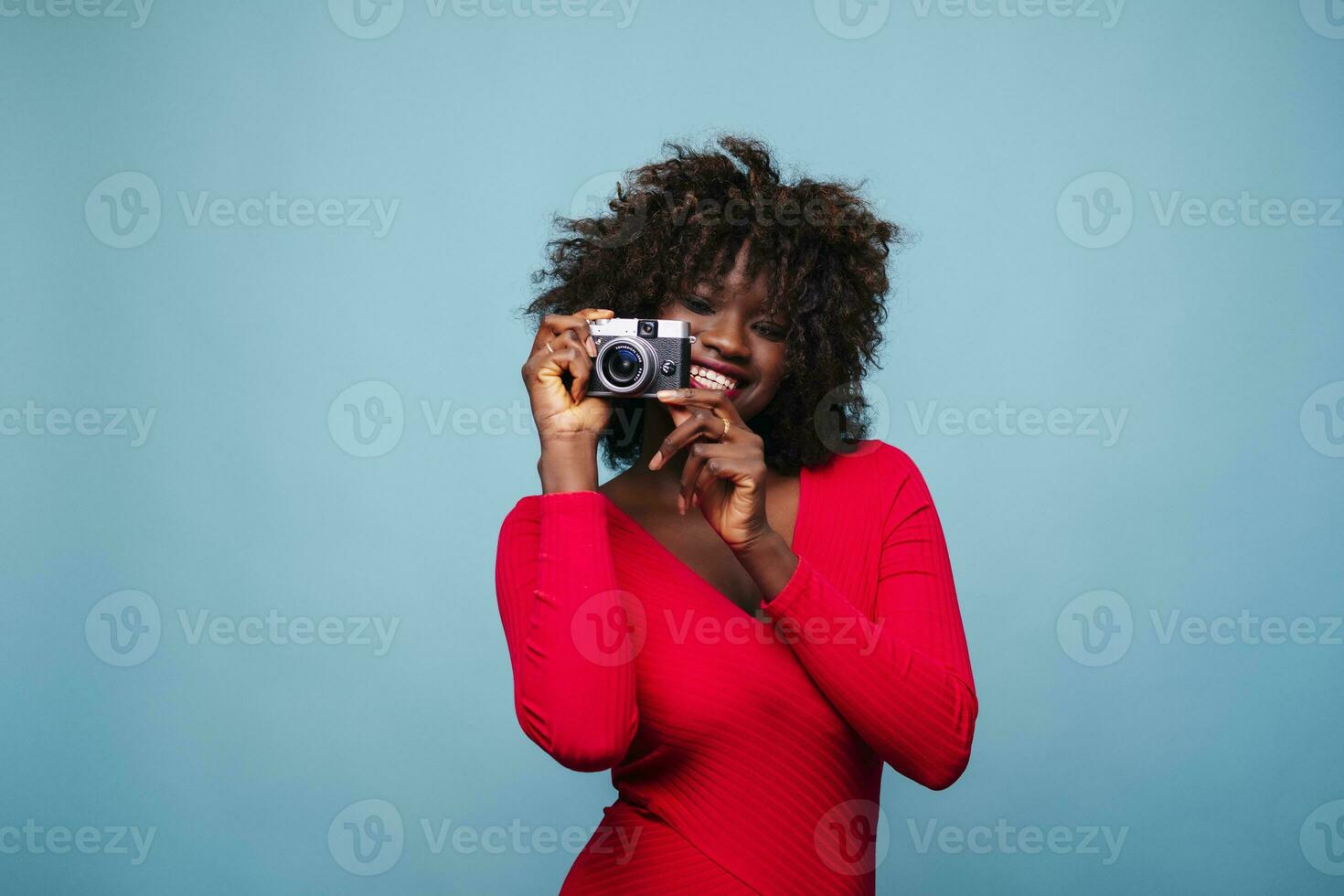 Portrait of happy young woman holding vintage camera in studio photo