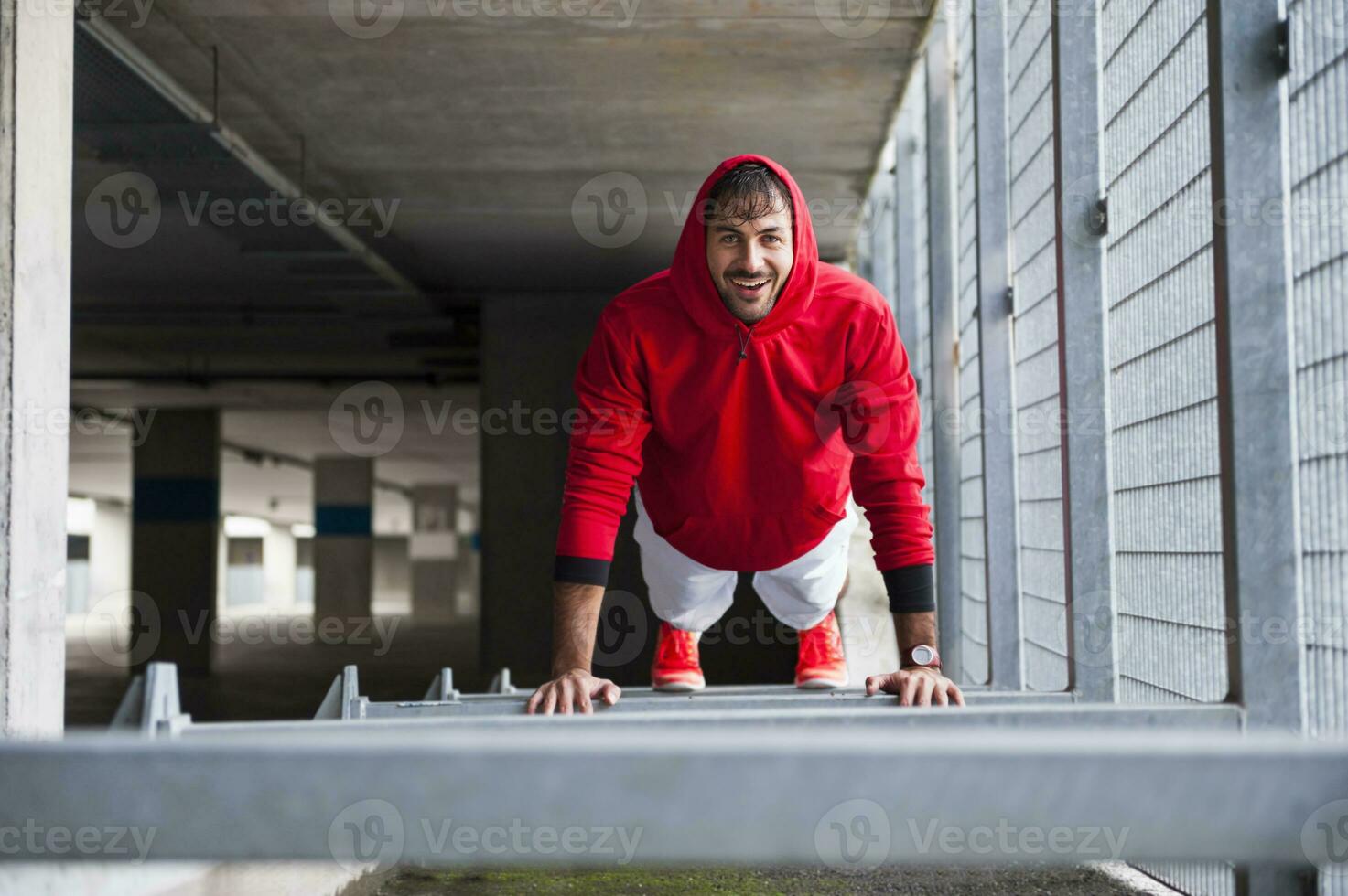 Portrait of happy young man doing push-ups in a car park photo