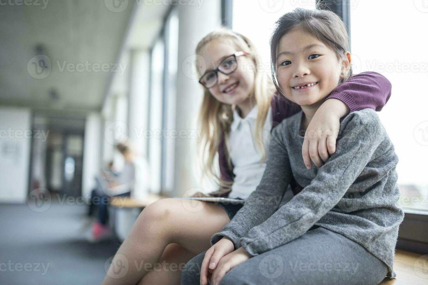 retrato de dos sonriente colegialas sentado en colegio corredor foto