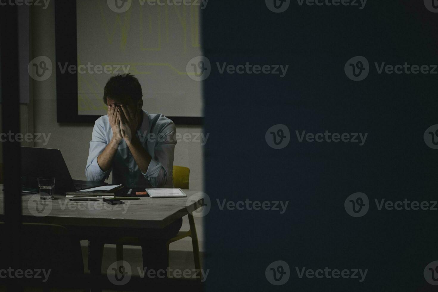 Exhausted businessman covering face, sitting in office, working late photo