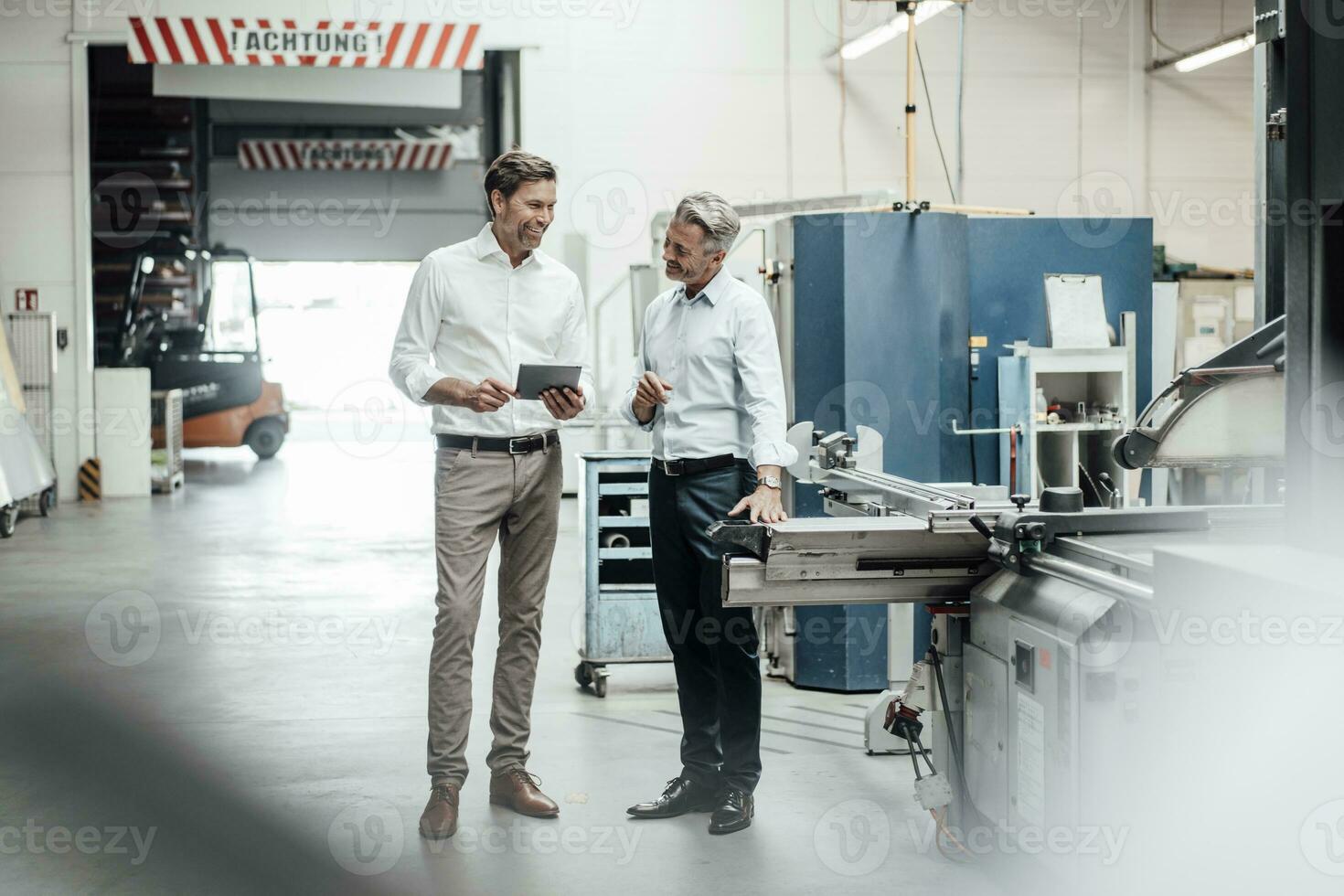 Happy mature businessmen discussing while standing in factory photo