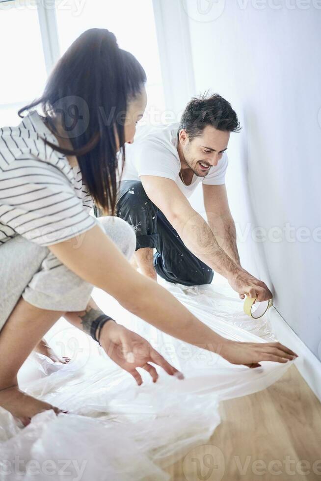 Happy couple preparing to paint the wall together photo