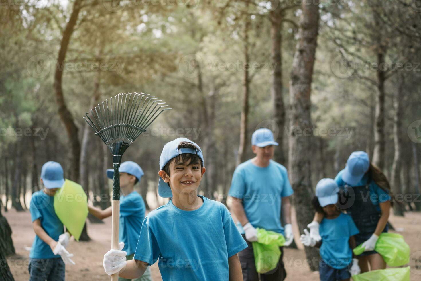 Portrait of a boy with group of people collecting garbage in a park photo