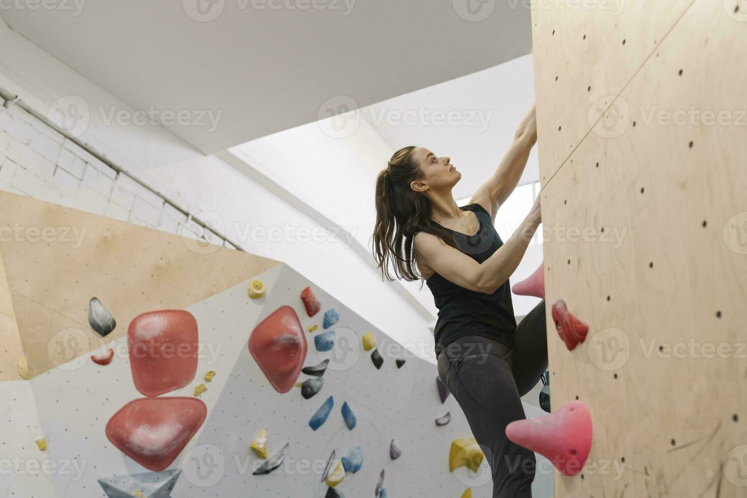 Woman bouldering in climbing gym photo