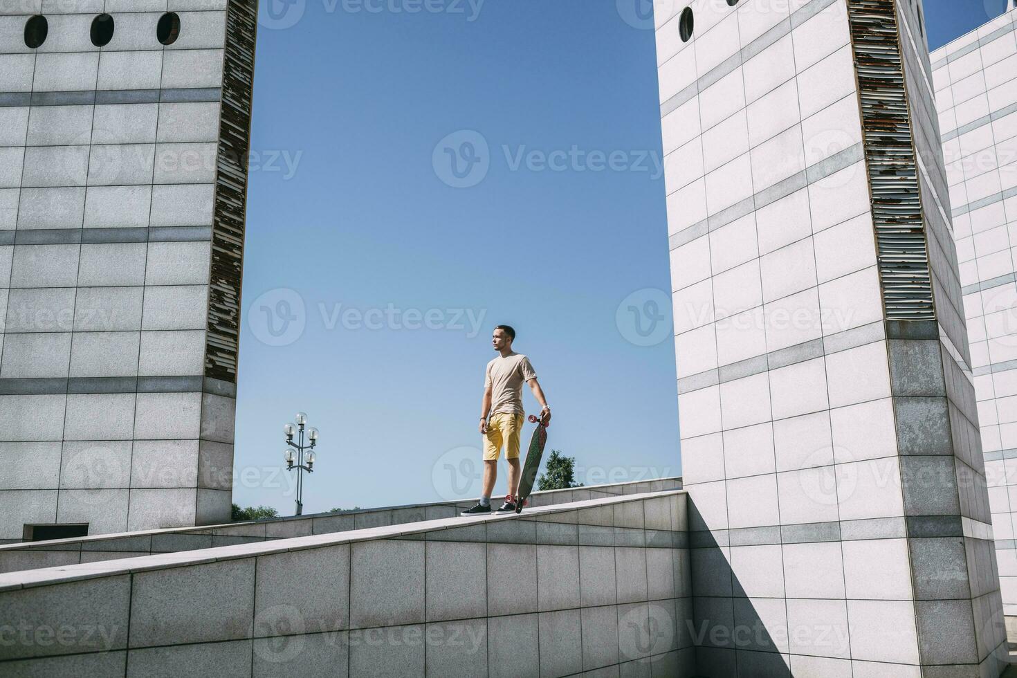 Young man with longboard surrounded by modern architecture photo