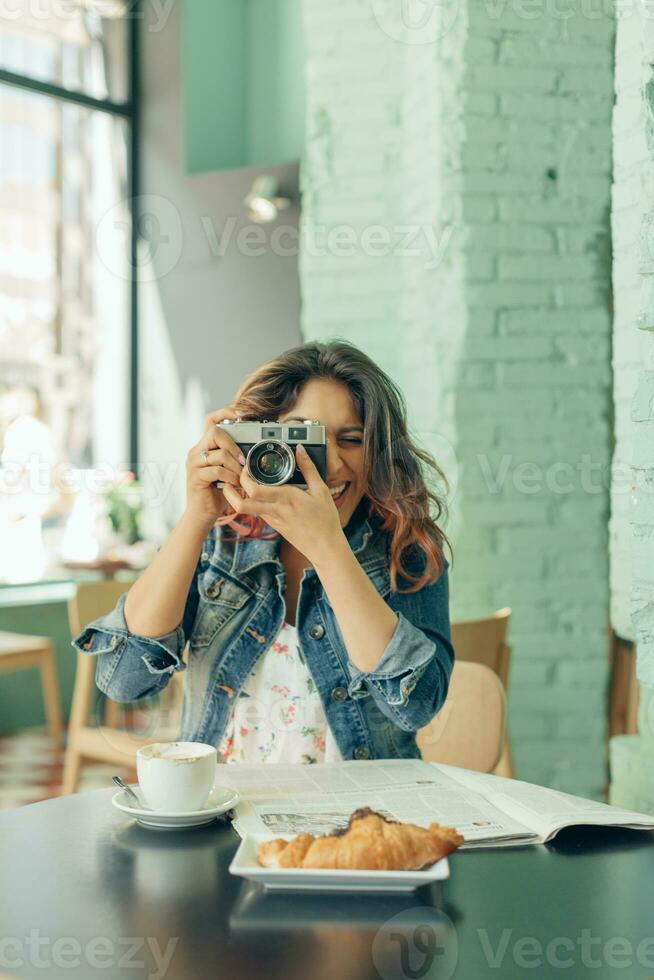 Laughing woman sitting at coffee shop taking pictures with camera photo