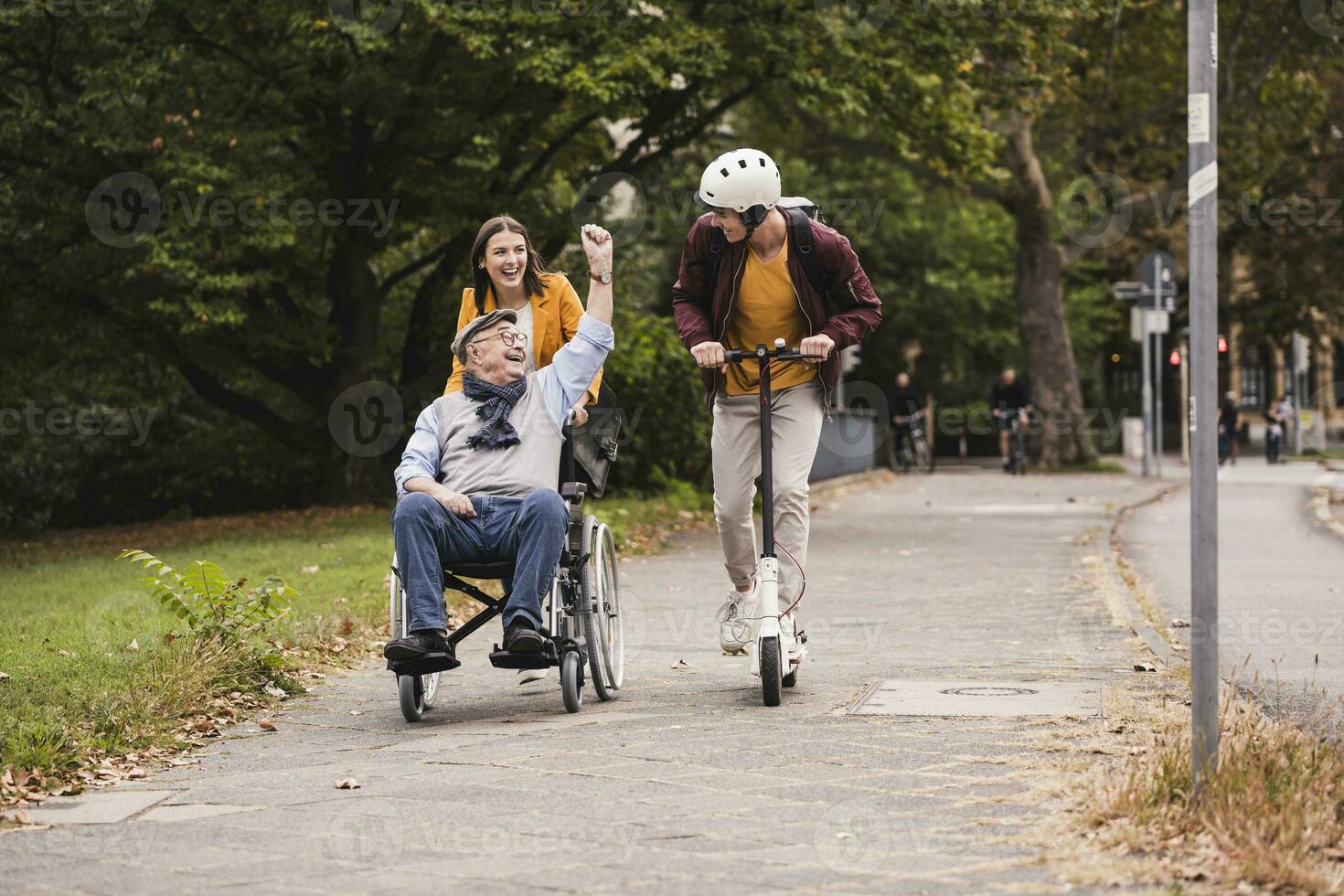 Senior man in wheelchair having fun with his adult grandchildren outdoors photo