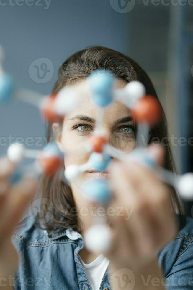 Female scientist studying molecule model, looking for solutions photo