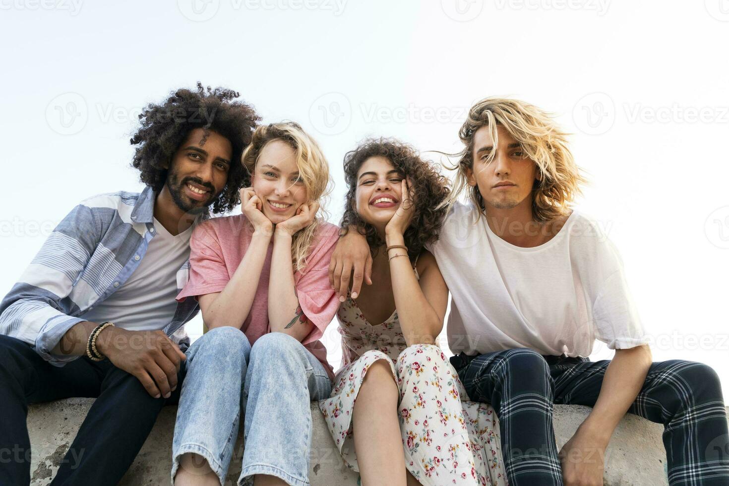 Portrait of happy friends sitting on a wall outdoors photo