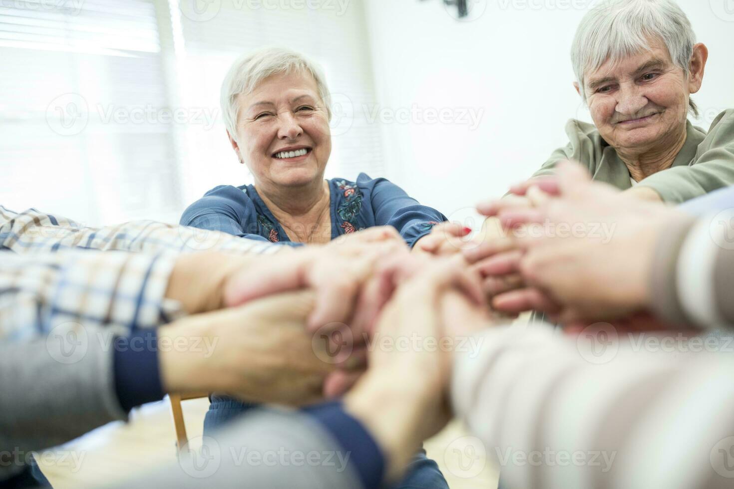 Group of active seniors stacking hands, symbolizing solidarity photo