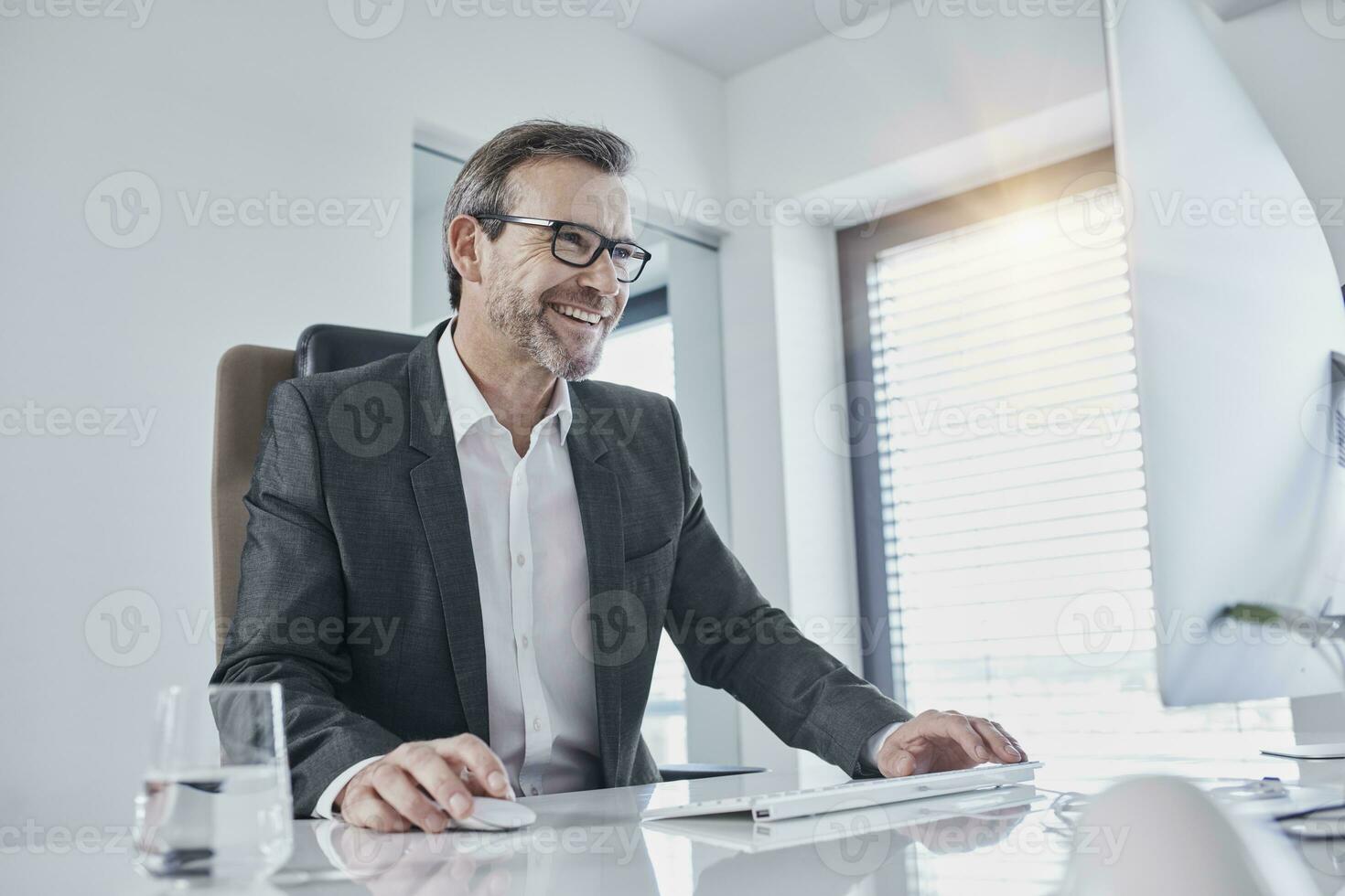Happy businessman working at desk in office photo