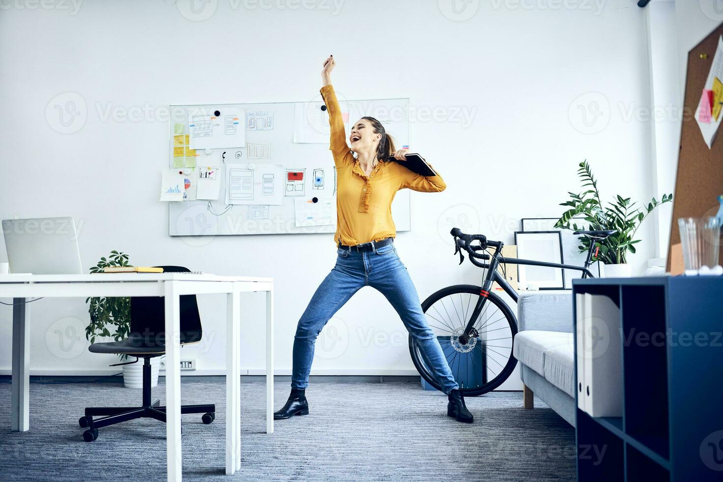 Happy young businesswoman cheering in office photo