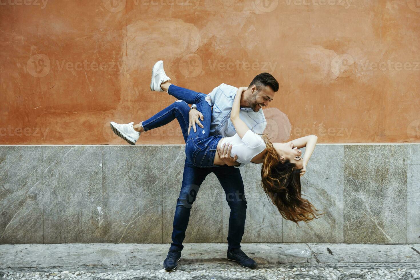 Carefree couple in love in front of a wall outdoors photo