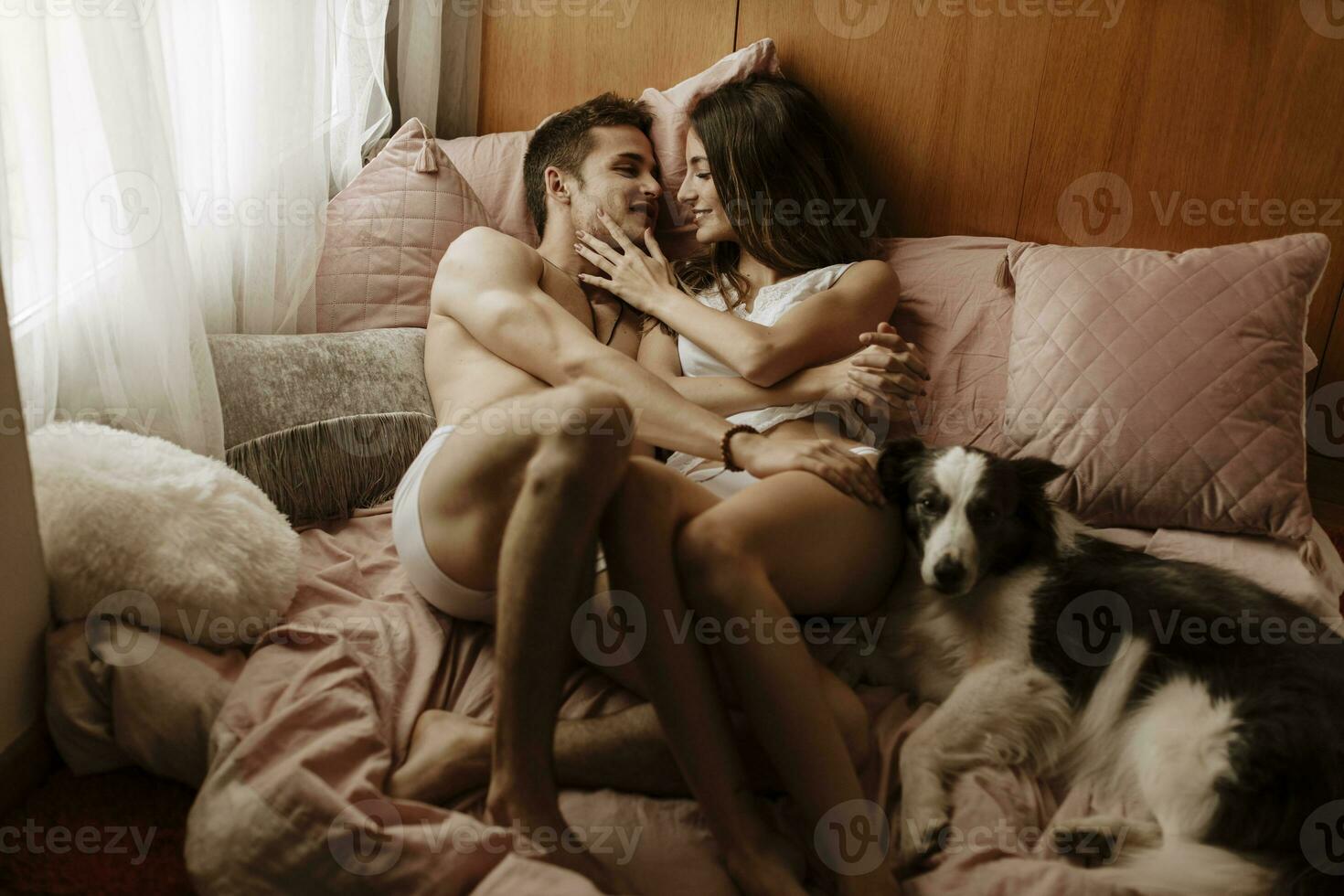Happy young couple and dog lying in bed photo