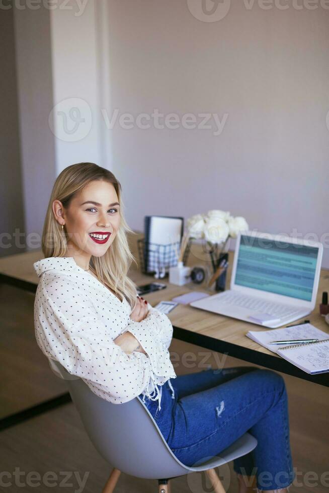 Blond businesswoman sitting at desk, working photo