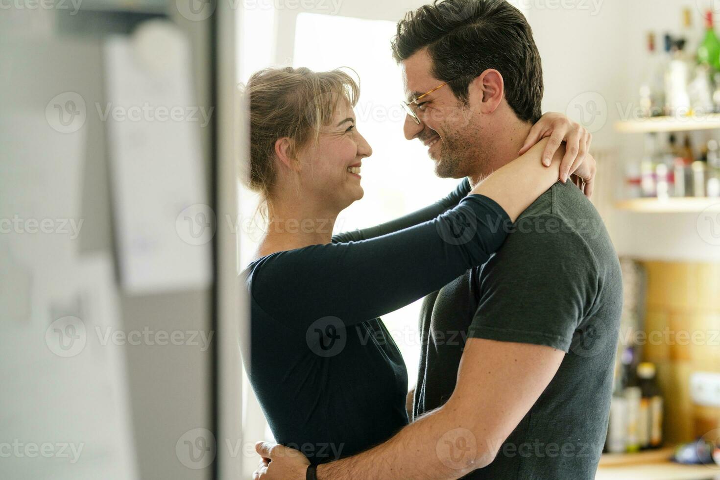 contento Pareja abrazando en cocina a hogar foto