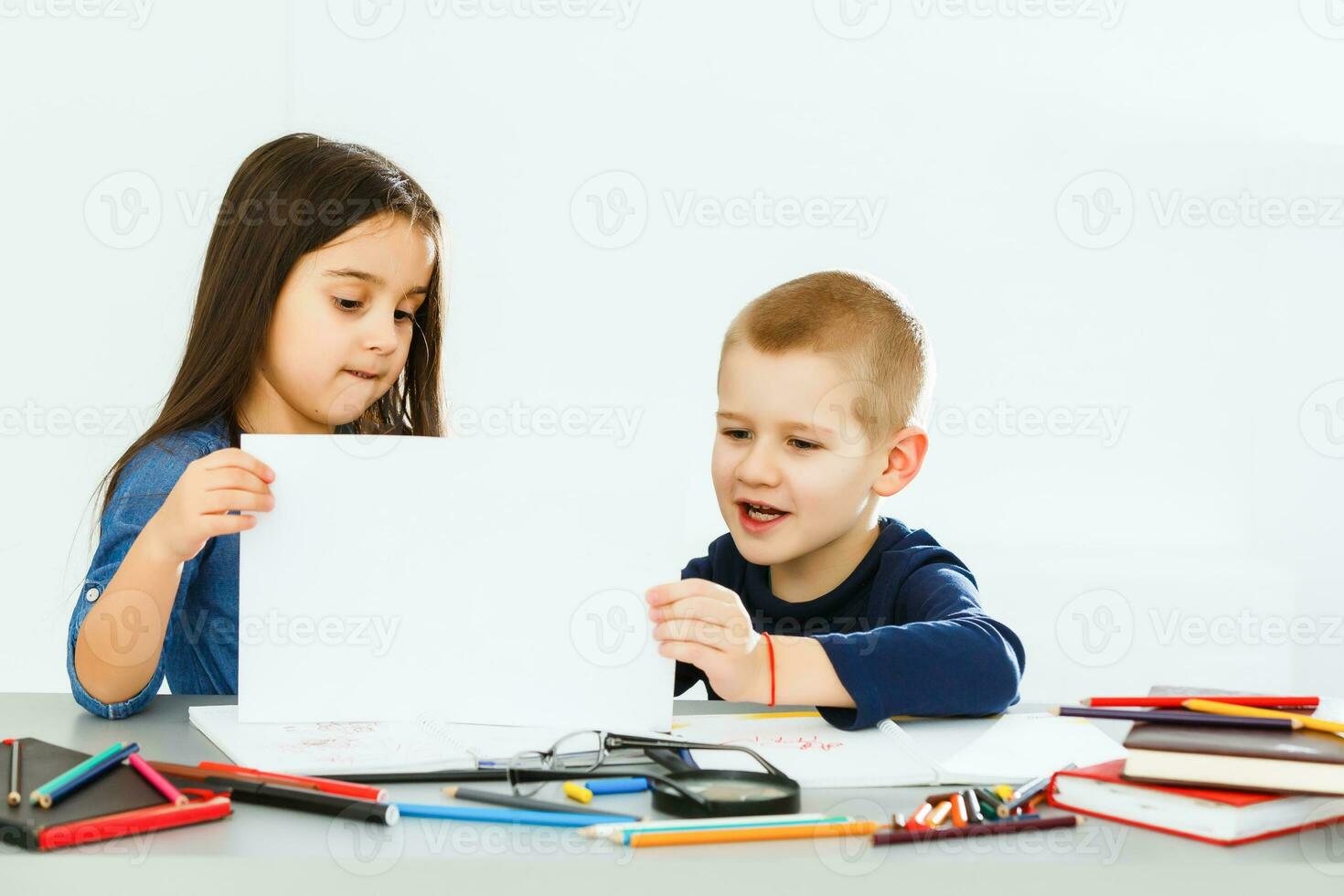 two cute smiling schoolchildren with blank sheet of paper in hands photo