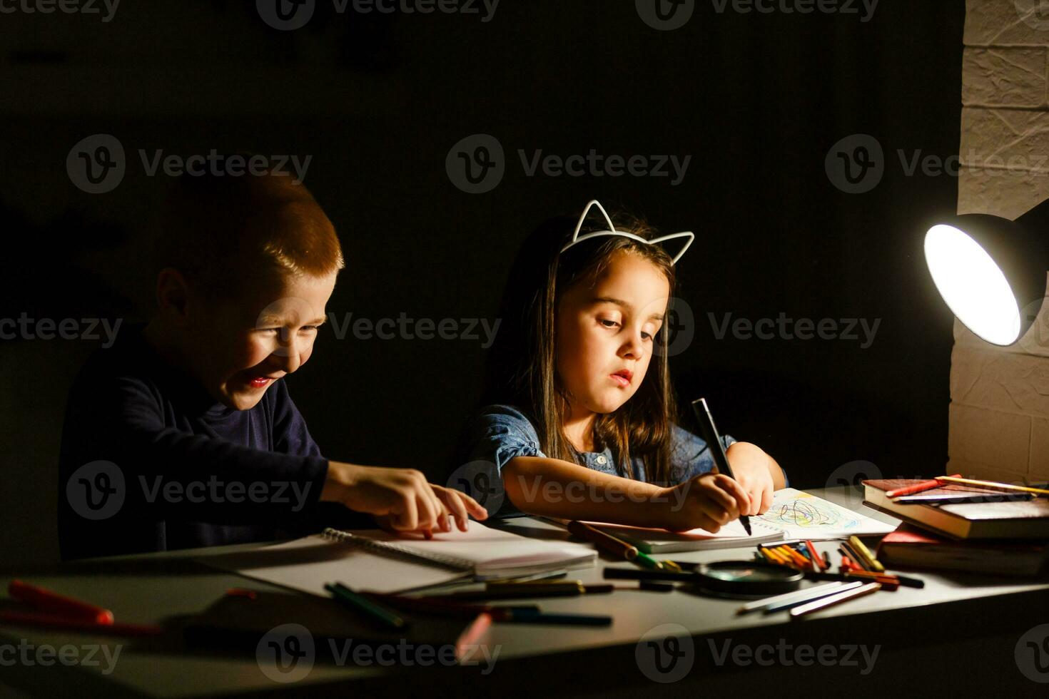 Little American girl boy doing homework in evening at home photo