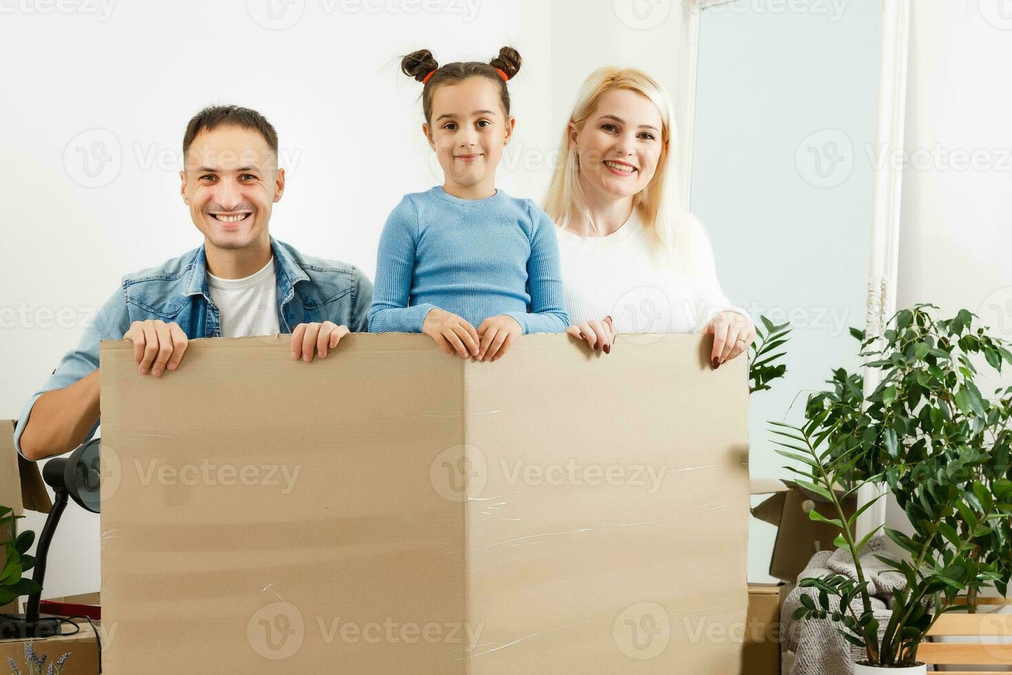 contento familia sentado en de madera piso. padre, madre y niño teniendo divertido juntos. Moviente casa día, nuevo hogar y diseño interior concepto foto