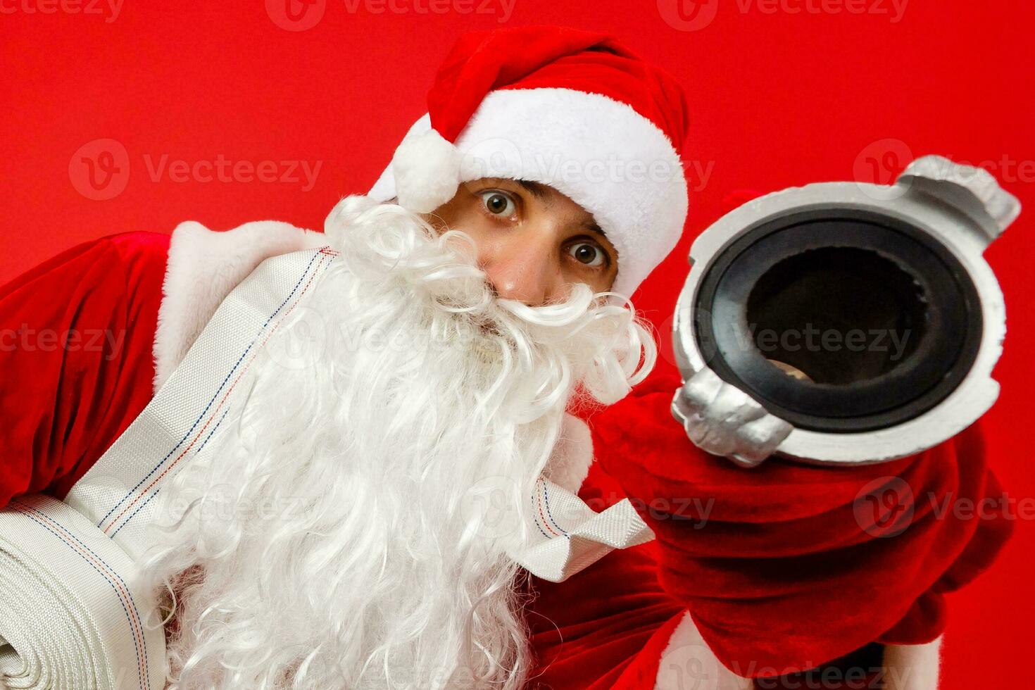 Navidad hombre en Papa Noel ropa con fuego manguera en pie en contra aislado rojo antecedentes foto