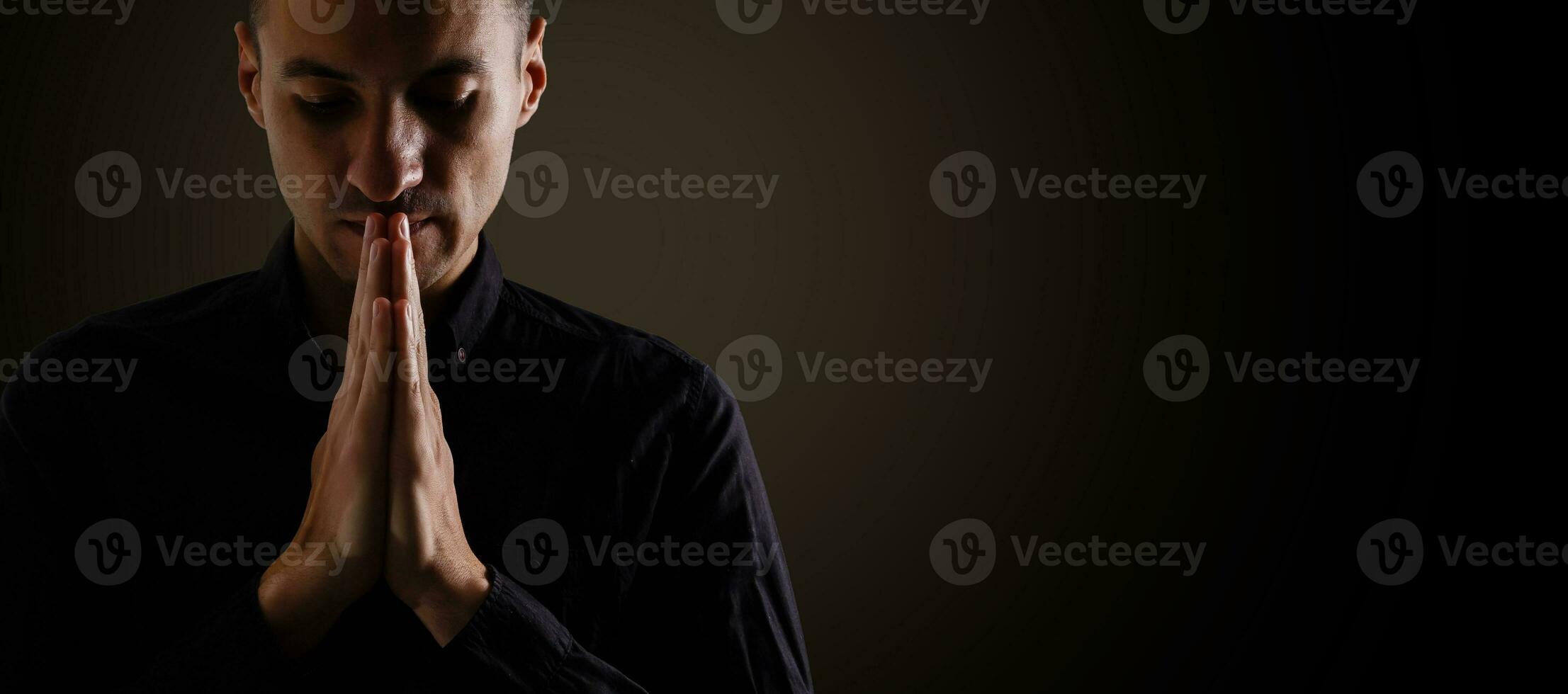 Low-key portrait of businessman praying for success photo