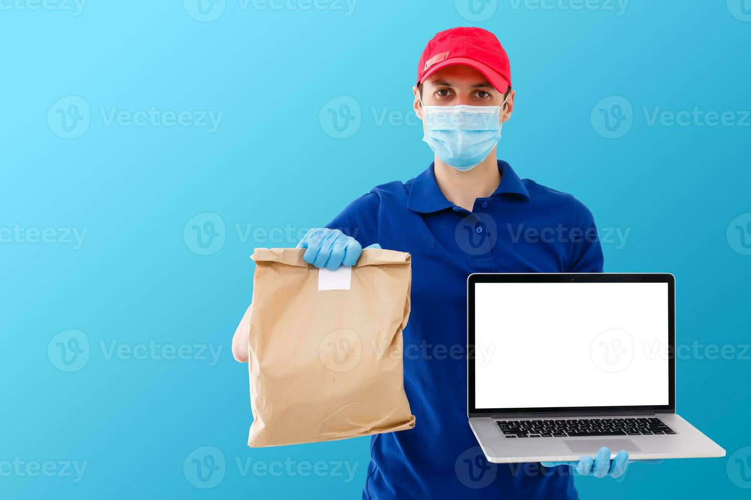 Delivery man in uniform hold craft paper packet with food isolated on blue background. Male employee in cap t-shirt working as courier. Service concept. Mock up copy space photo