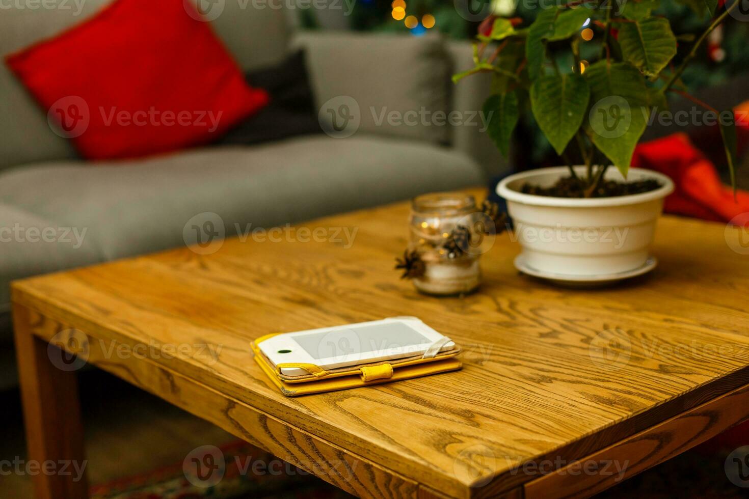 Modern Christmas interior of bar or cafe. Composition with pine cones on a table, cosy sofa with red pillow, smartphone photo