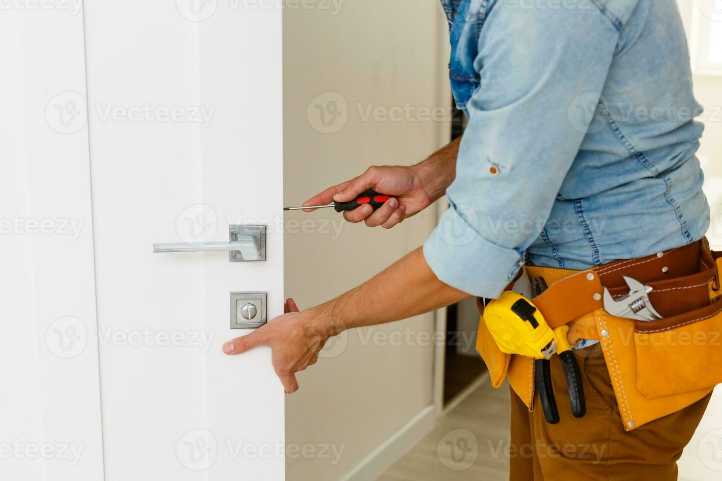 young repairman checking new door lock photo