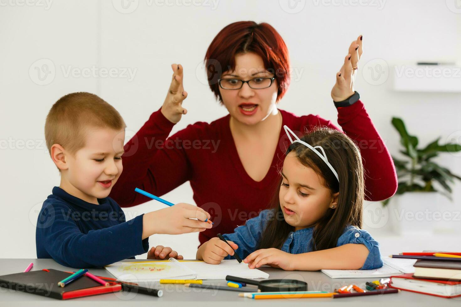 Female teacher helping children with homework in classroom at school photo