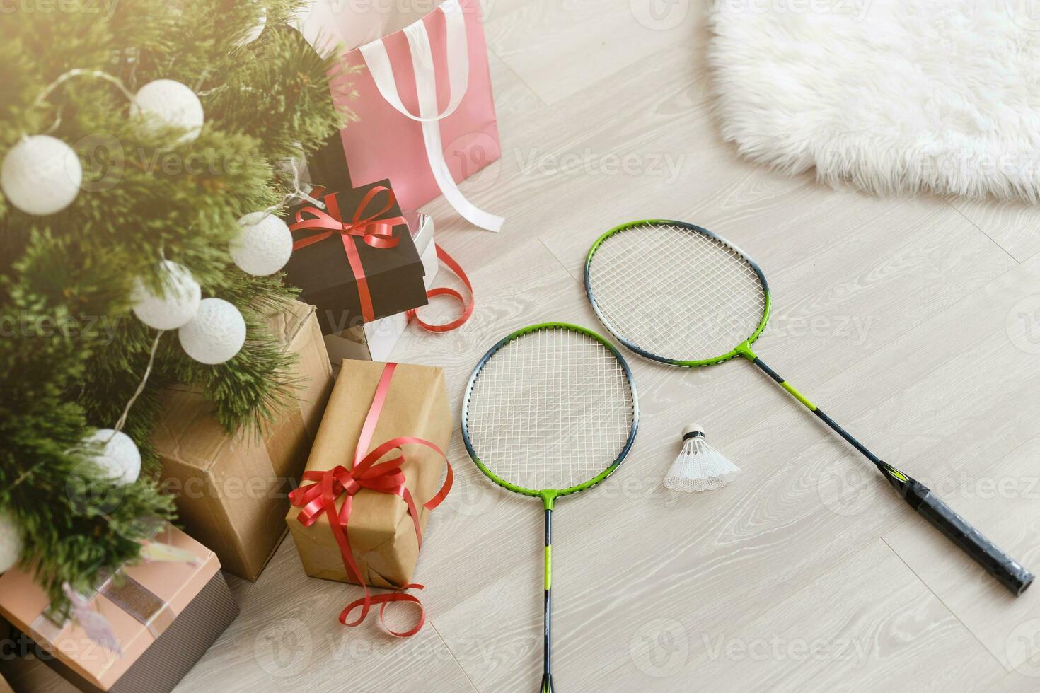 gifts and a tennis racket lie near a Christmas tree photo