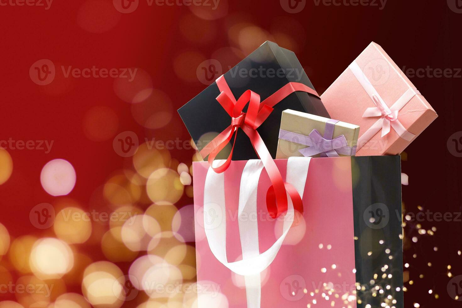 Holiday shopping bags and gift boxes on dark background, light bokeh photo