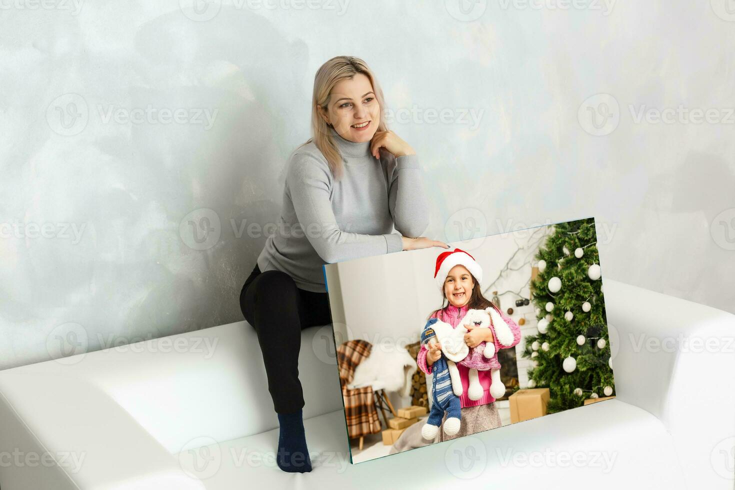 Young girl holds photo canvas at home on the couch