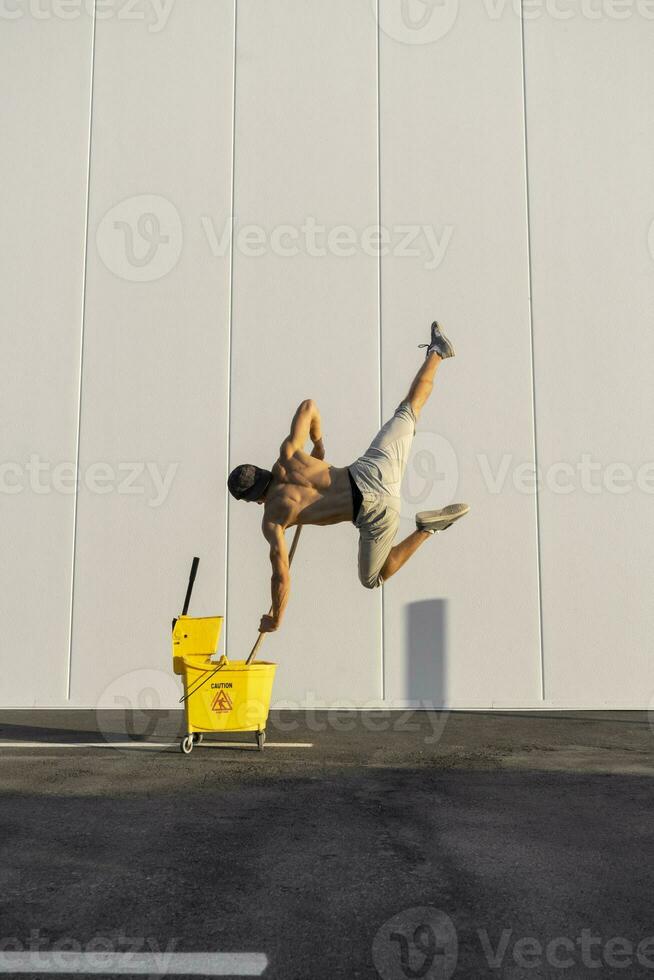 Acrobat playing with cleaning bucket and mop photo